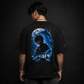 Person wearing a black t-shirt with a blue and white graphic on the back against a dark background